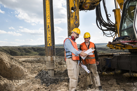 Engineer directs manual worker in front of drilling vehicle