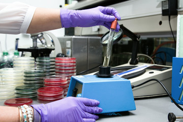 scientist at work holding a tube in the machine fluid mixer in t