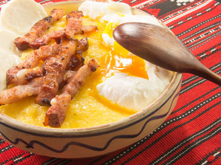 polenta bulz with fried bacon cheese and eggs and wooden spoon