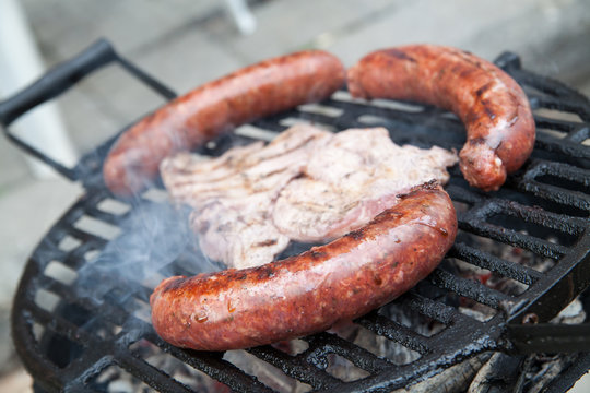 Grilling sausages and chop on barbecue grill