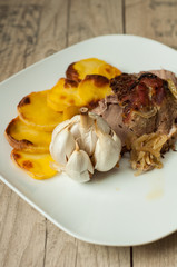 roasted pork with garlic and potatoes on white plate