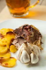 roasted pork with garlic and potatoes on white plate