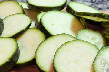 Freshly sliced cucumbers on wooden cutting board with knife. Who