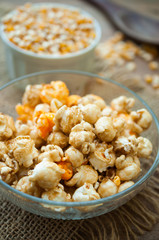 A bowl of popcorn on a wooden table, caramel popcorn