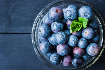 Blueberry in a glass bowl on the blue wooden table