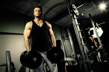Fototapeta na wymiar strong bodybuilder athlete with heavy dumbbells in gym