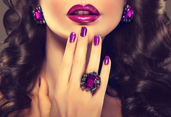 Beautiful girl showing purple manicure and stylish jewelry