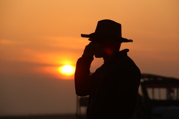 silhouette of man with phone at sun set