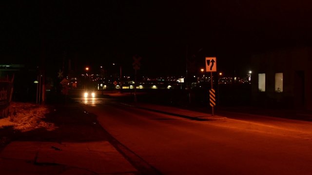 Cars at a train crossing at night
