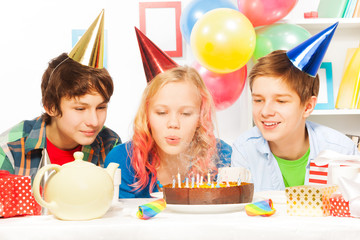 Beautiful teen girl blow cake on birthday party