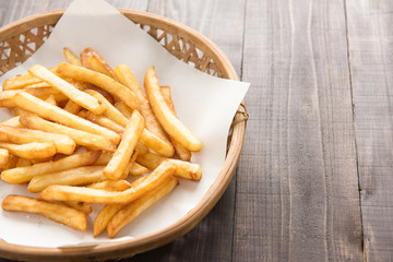Traditional french fries in basket on wooden background.