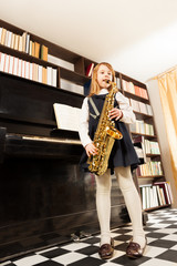 Girl in school uniform plays on alto saxophone