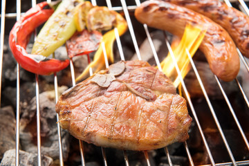 Pork chop steak and vegetable with sausage on a flaming BBQ gril