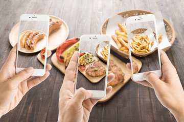 friends using smartphones to take photos of sausage and pork