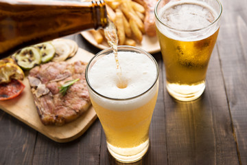 Beer being poured into glass with gourmet steak and french fries