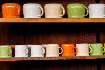 Colorful zinc cup on wooden shelves over wood background.