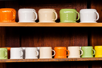 Colorful zinc cup on wooden shelves over wood background.