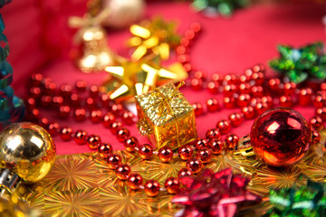 small golden gift-box near red bead and bow close-up