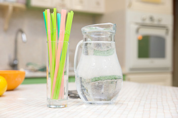 pitcher of water and glass of bright tubes on  kitchen table