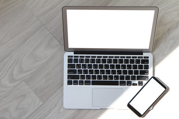 blank screen laptop computer with smart phone is on wooden desk