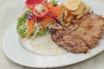 steaks and vegetable salad with french fries.