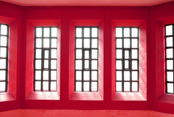 Abstract view of symmetrical windows on red wall