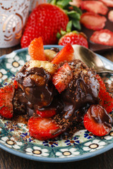 Fototapeta na wymiar Profiteroles with strawberries and chocolate sauce