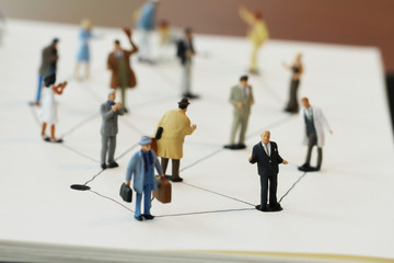 close up of miniature people with social network diagram on open