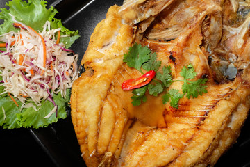 fried fish with fresh herbs and sweet spicy sauce on plate in bl