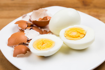 Hard boiled egg with peeled and shattered shells on plate