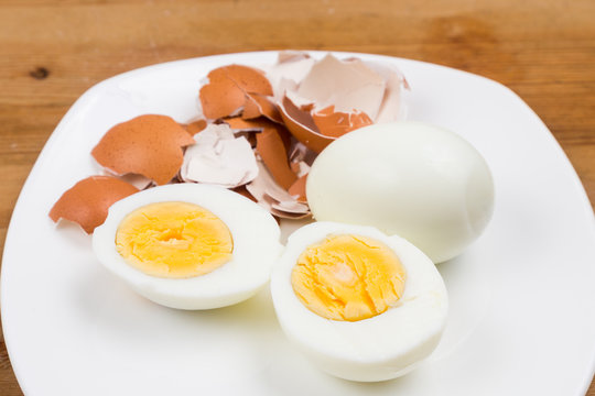 Hard boiled egg with peeled and shattered shells on plate