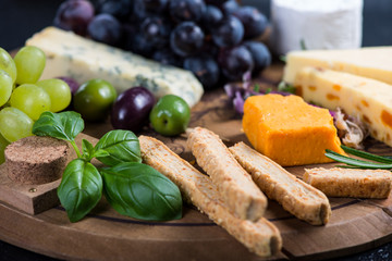 Cheese board with fresh grapes,herbs and olives