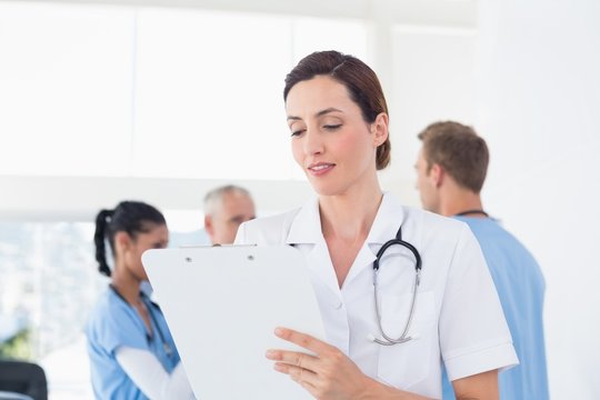 Confident female doctor holding clipboard