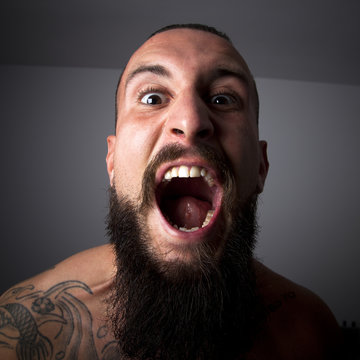 Hombre con barba y tatuaje gritando