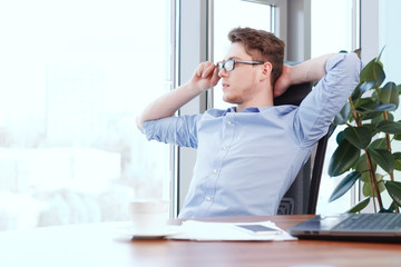Fototapeta premium Businessman at desk with hands behind his head 