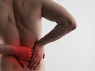 Closeup of male back massaging his sore loin or hip. Health care