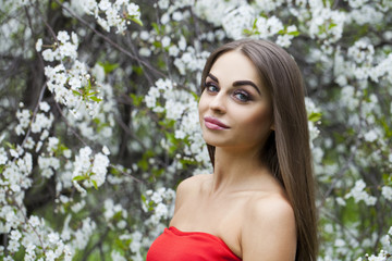 Naklejka premium Portrait of a beautiful young girl in red dress on the backgroun