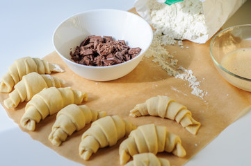 Fototapeta na wymiar Croissants cooking on white table with flour and baking paper