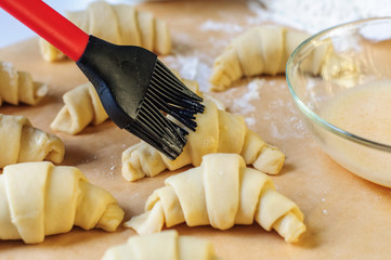 Croissants cooking and brushing with egg on  table with flour