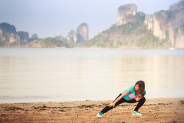 Naklejka premium girl does gymnastics on beach at dawn