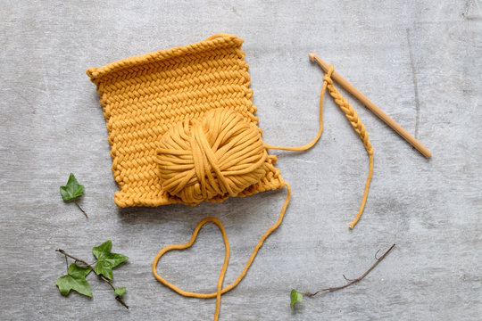 Ball of yellow yarn with crochet hook