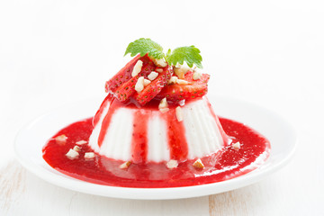 Vanilla panna cotta with strawberry sauce and nuts on a plate