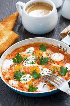 fried quail eggs in tomato sauce in a frying pan for breakfast
