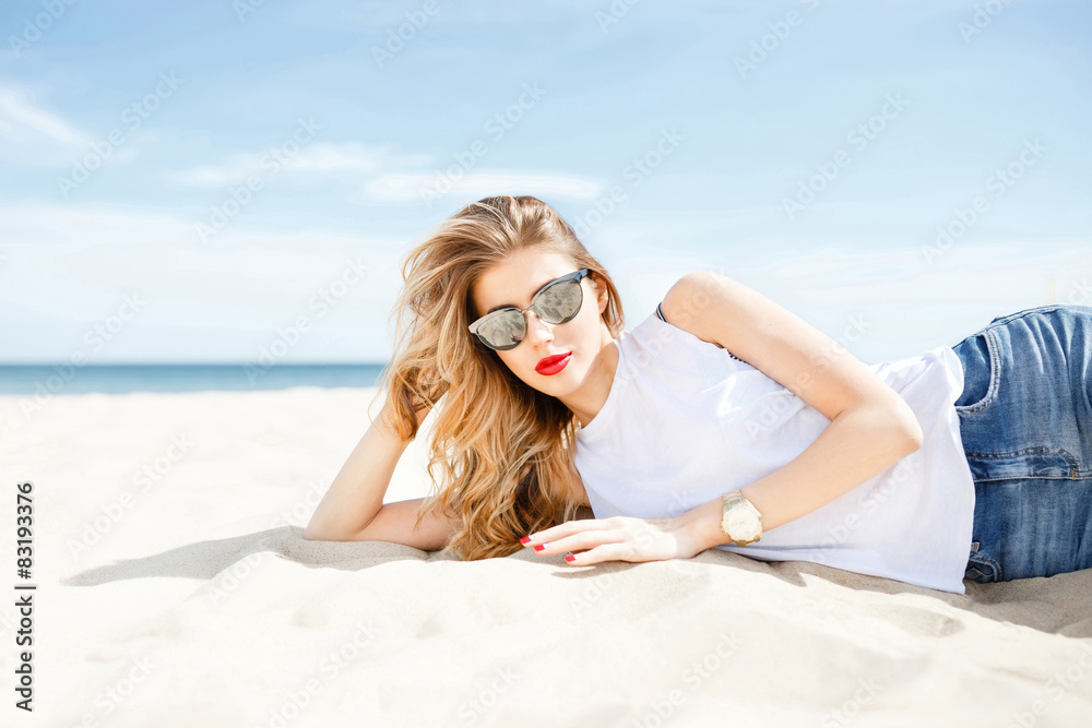 Wall mural attractive girl in sunglasses posing lying on the sea beach