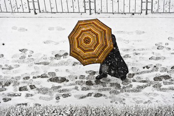 Spacer po chodniku z parasolem w opadach śniegu