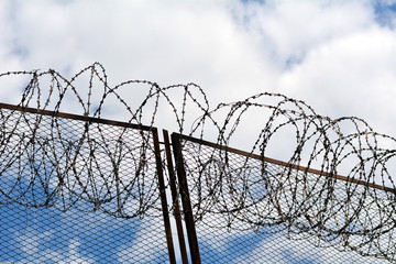 Колючая проволока на заборе тюрьмы, промышленного объекта - obrazy, fototapety, plakaty