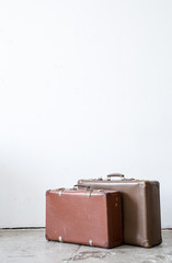 Vintage leather suitcase on white wall.