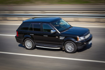 Obraz na płótnie Canvas black Range Rover SUV quickly goes on the road
