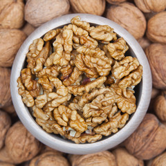 Walnuts in a wooden bowl on a walnuts pile