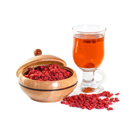 Glass healing infusion of goji berries and dried berries nearby.